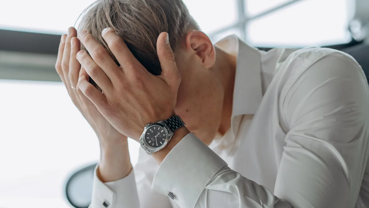 A business professional showing stress and fatigue with head in hands.
