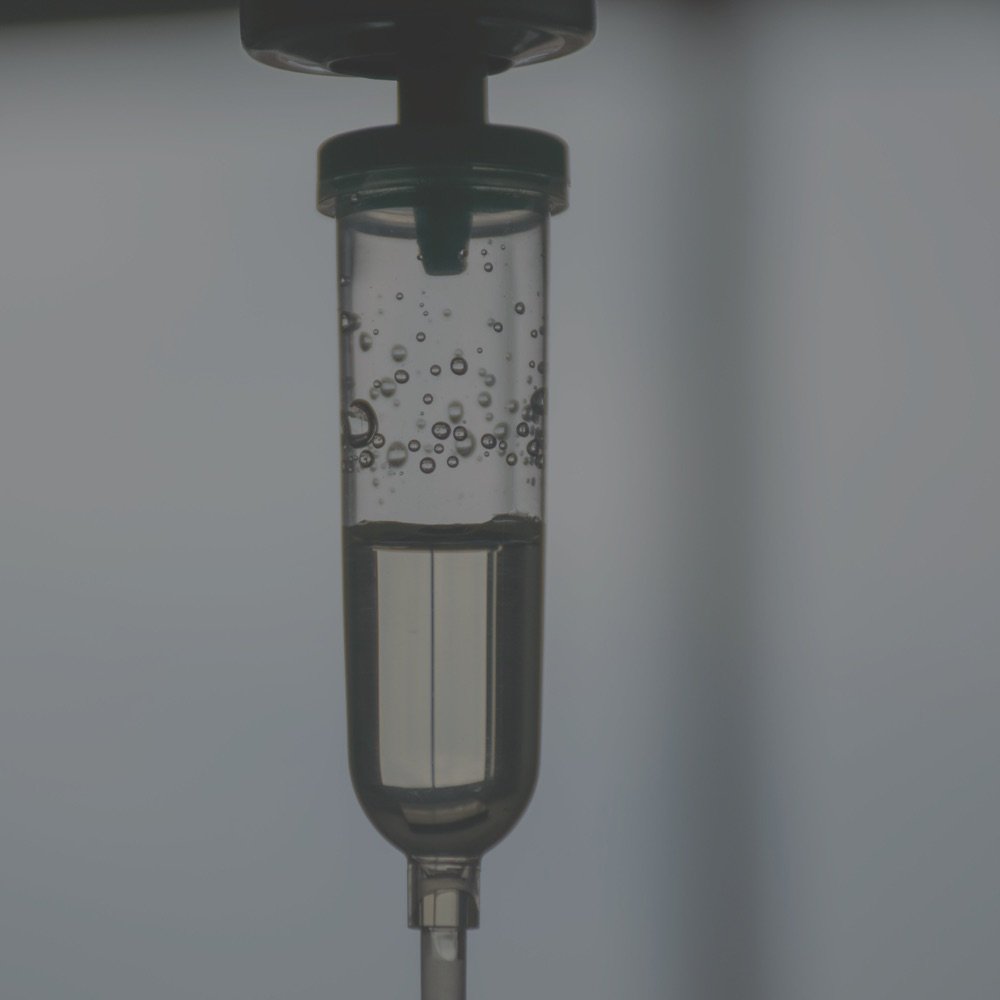 Close-up of an intravenous drip chamber with fluid running through it during infusion therapy.