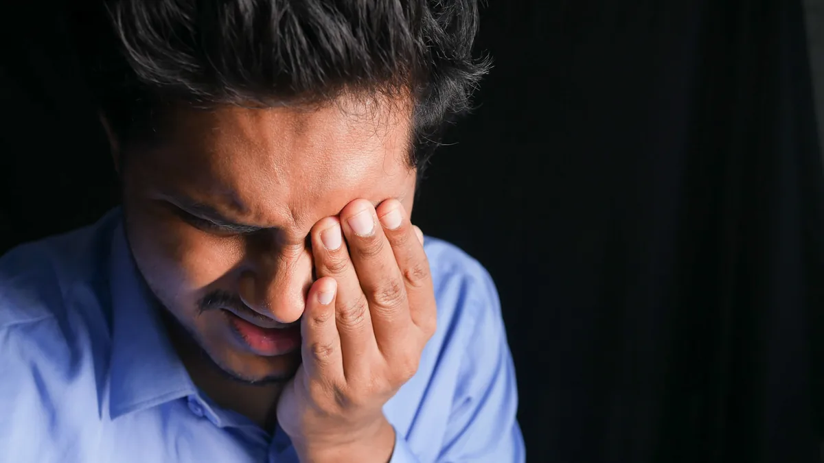 A man presses his hand over one eye during a severe one-sided headache