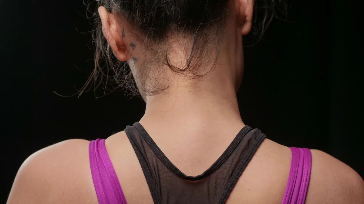 The back of a woman's head and neck, the region the greater and lesser occipital nerves supply
